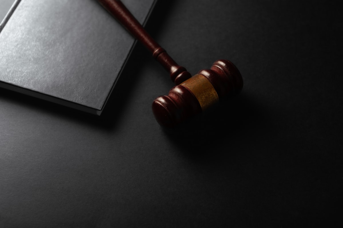 Wooden gavel resting on a dark surface next to a book